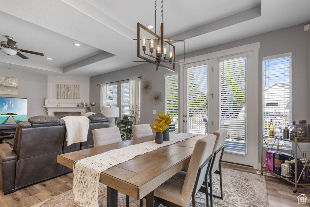 Dining area featuring a tray ceiling, recessed lighting, light wood-style flooring, a chandelier, and a ceiling fan