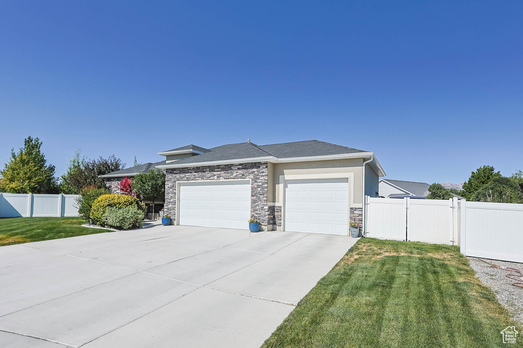 Prairie-style home featuring an attached garage, concrete driveway, and stone siding