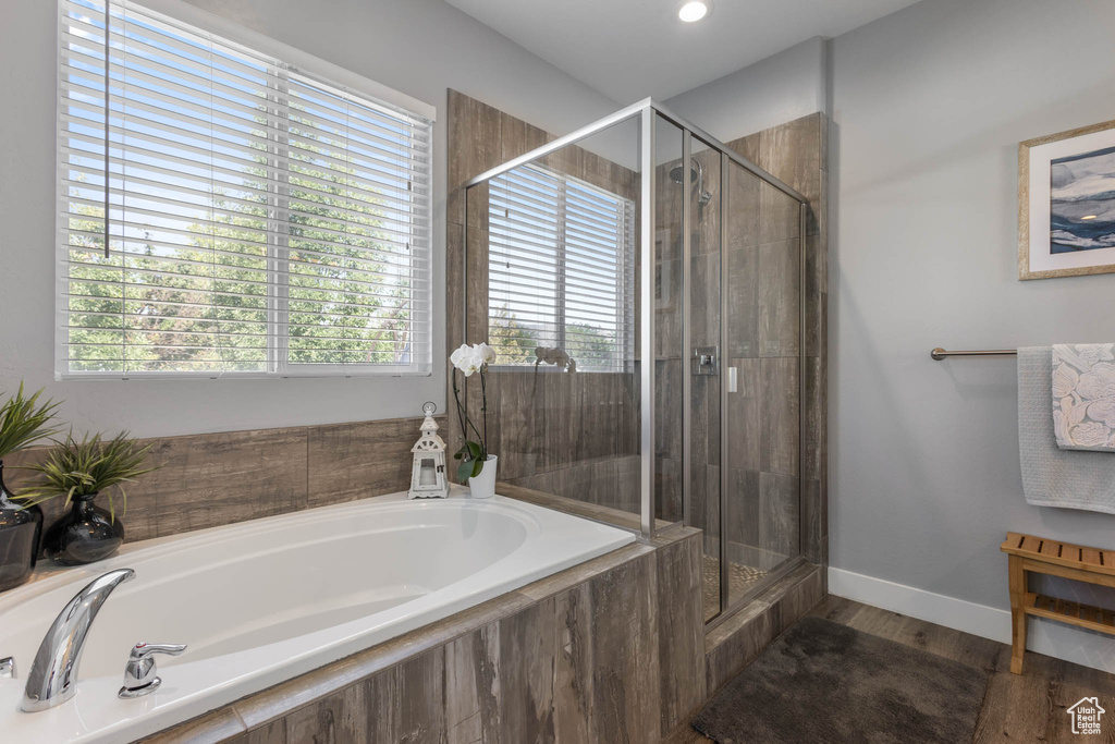 Full bathroom featuring a stall shower, a bath, and wood finished floors