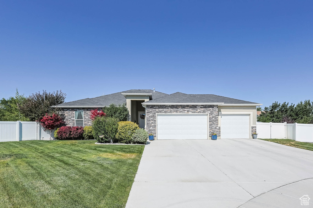 Prairie-style home with stone siding, an attached garage, and driveway