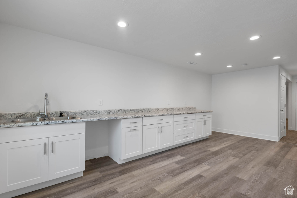Kitchen with recessed lighting, wood finished floors, white cabinets, and light stone counters