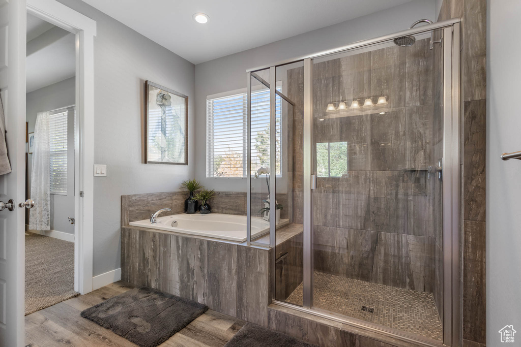 Full bathroom featuring a bath, a stall shower, wood finished floors, and recessed lighting