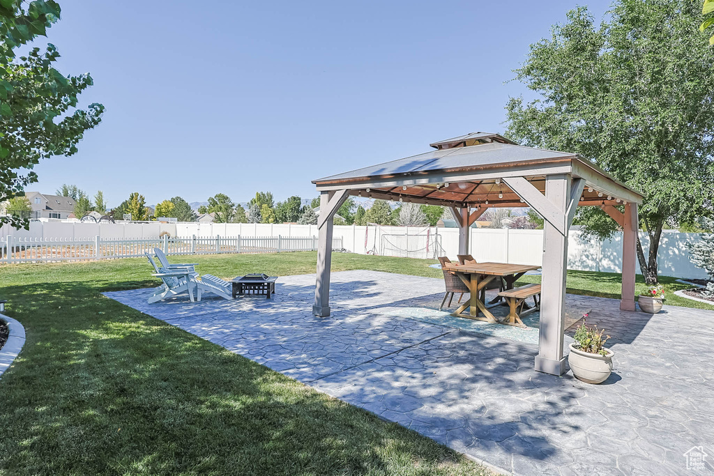 Fenced backyard featuring an outdoor fire pit, a gazebo, a patio area, and outdoor dining area