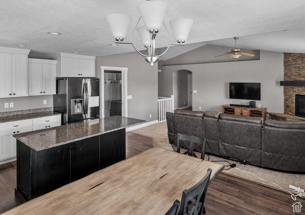 Kitchen with fridge with ice dispenser, arched walkways, a ceiling fan, a kitchen island, and lofted ceiling