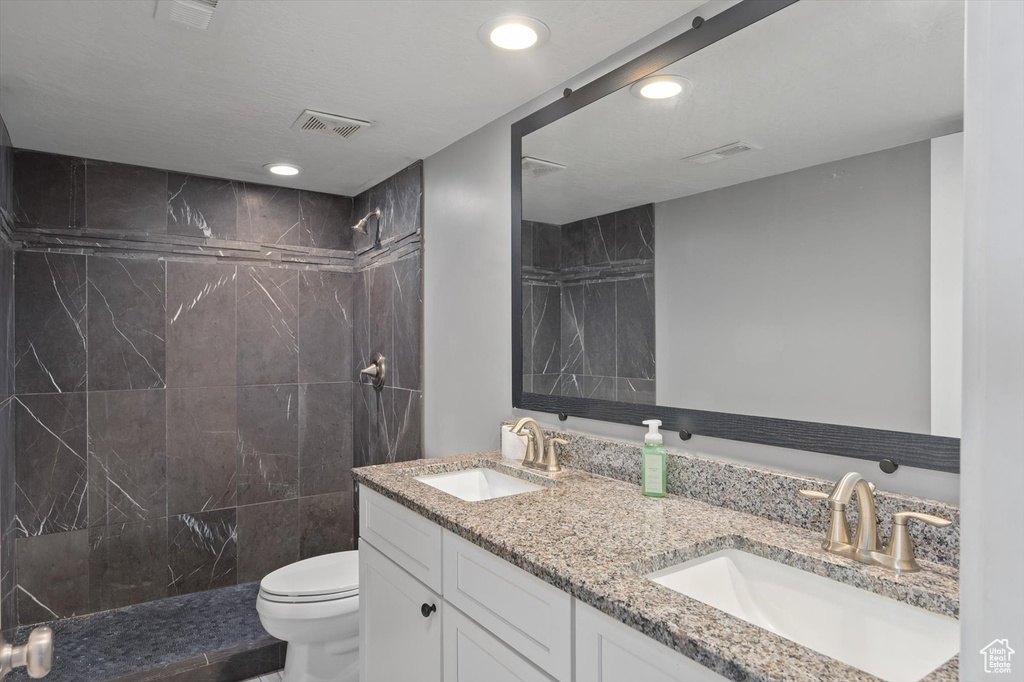Full bathroom featuring double vanity, tiled shower, and recessed lighting