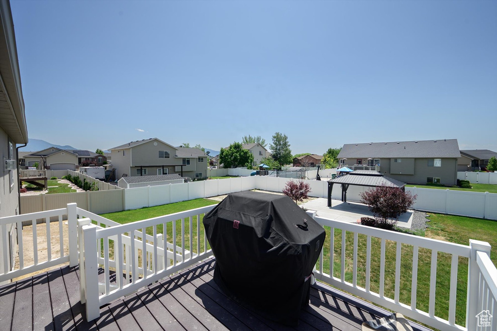Wooden terrace featuring a residential view, a gazebo, area for grilling, and a fenced backyard