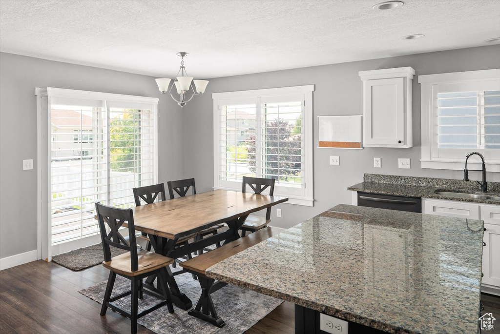 Dining space featuring dark wood-style floors, a textured ceiling, and a chandelier