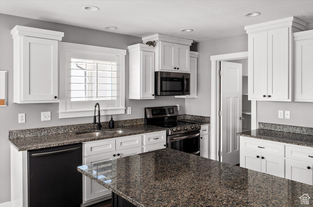 Kitchen with appliances with stainless steel finishes, white cabinets, dark stone counters, and recessed lighting