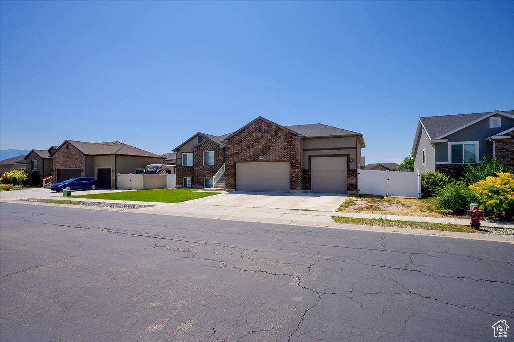 View of front of home featuring a gate, an attached garage, brick siding, driveway, and a residential view