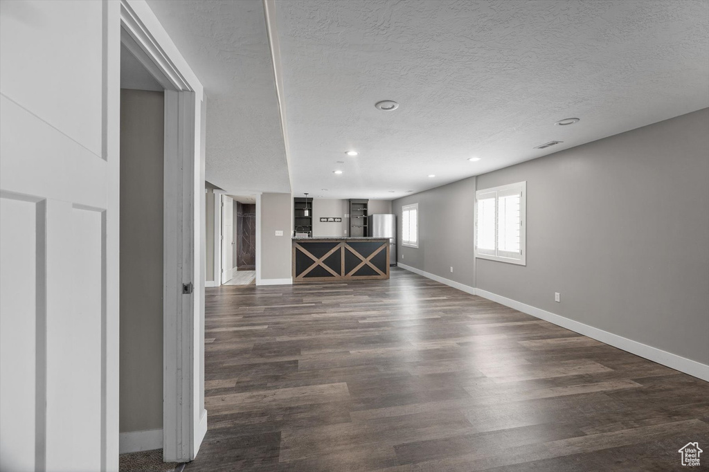 Empty room with dark wood-style flooring, a textured ceiling, and recessed lighting