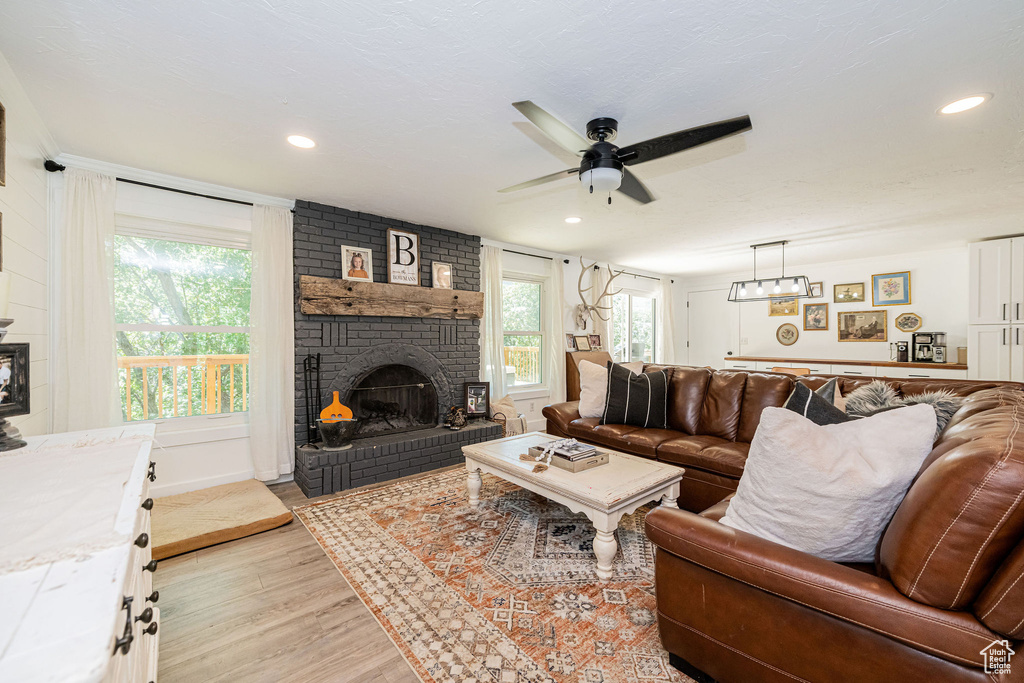 Living area featuring a brick fireplace, ceiling fan, plenty of natural light, light wood-style flooring, and recessed lighting