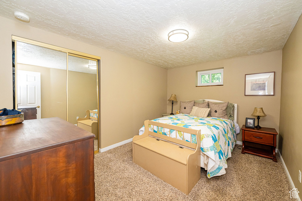 Bedroom with carpet, a textured ceiling, and a closet