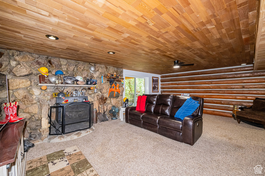 Carpeted living room with rustic walls, wooden ceiling, and a ceiling fan