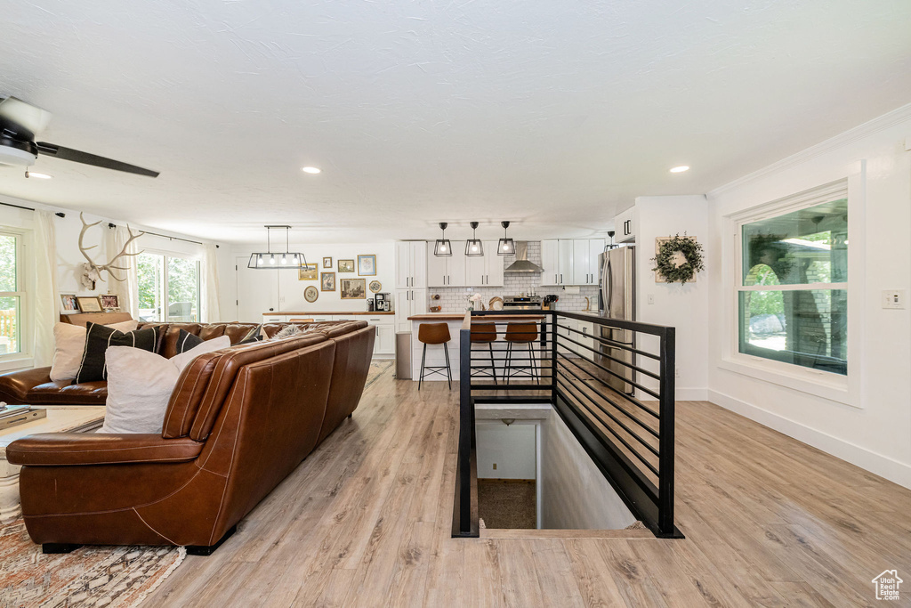 Living area featuring light wood-style flooring, ceiling fan, and recessed lighting