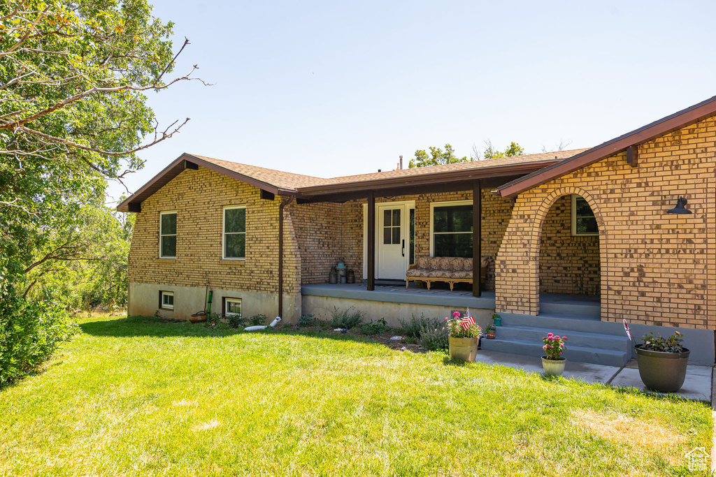 View of front of home featuring brick siding, covered porch, and a front lawn