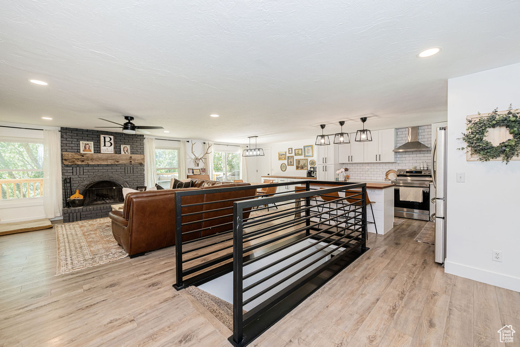 Living area featuring ceiling fan, light wood-style flooring, recessed lighting, and a brick fireplace
