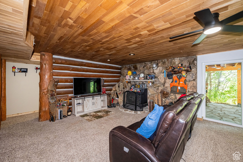 Carpeted living room featuring wood ceiling, rustic walls, and a ceiling fan