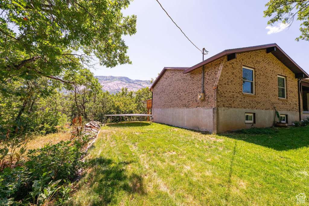 View of side of property with brick siding, a lawn, and a mountain view
