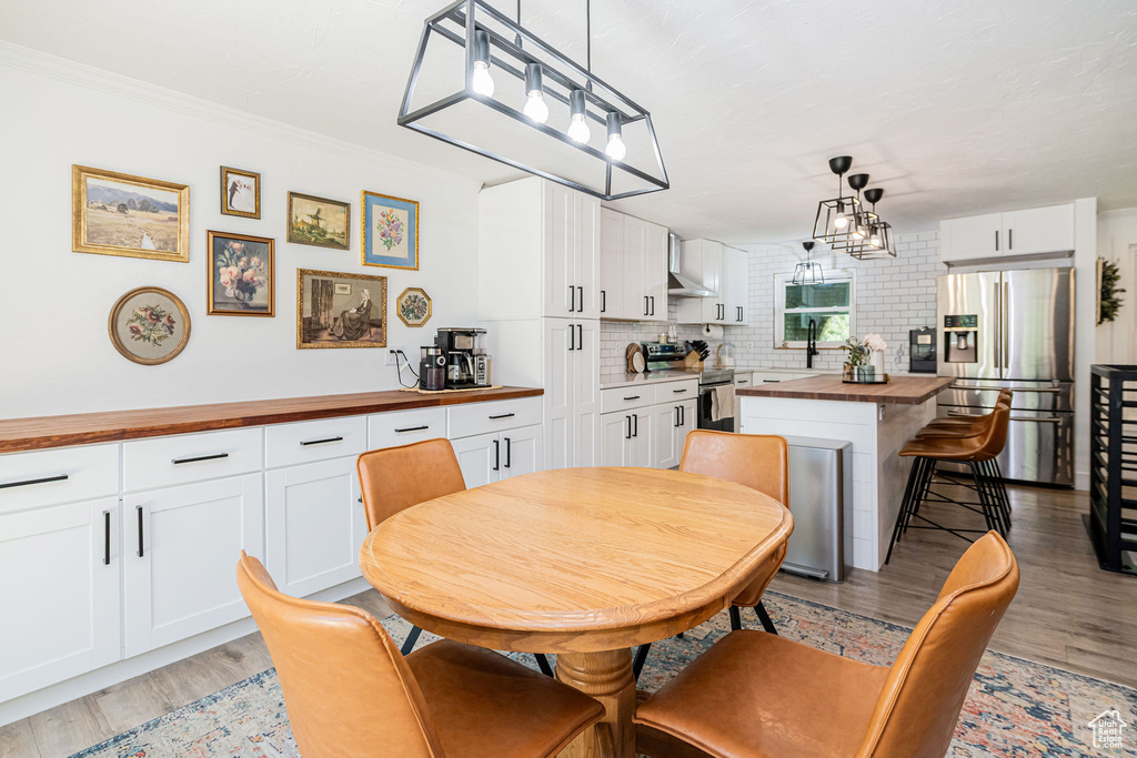 Dining area featuring light wood-type flooring and crown molding