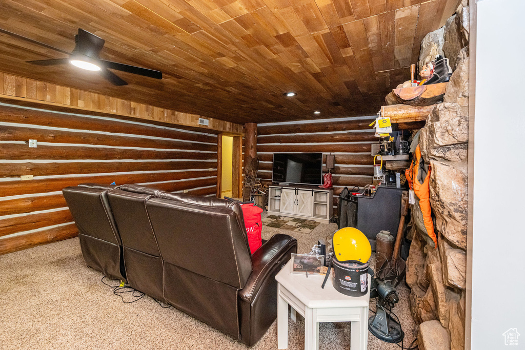 Living area with rustic walls, wood ceiling, carpet flooring, and a ceiling fan