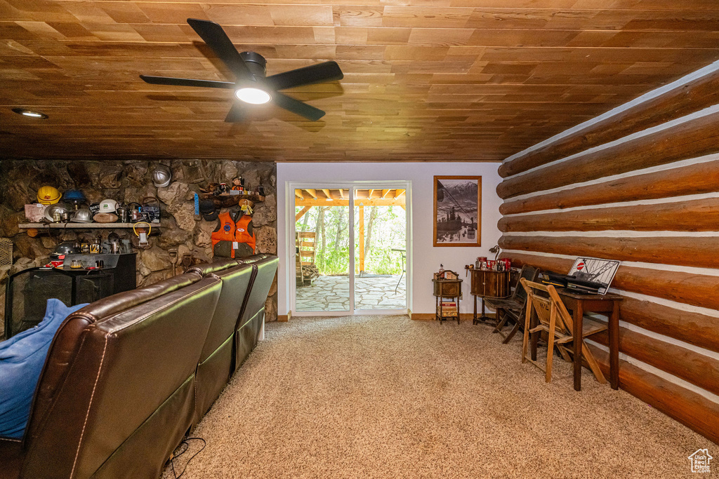 Interior space with wooden ceiling, a ceiling fan, light carpet, and rustic walls