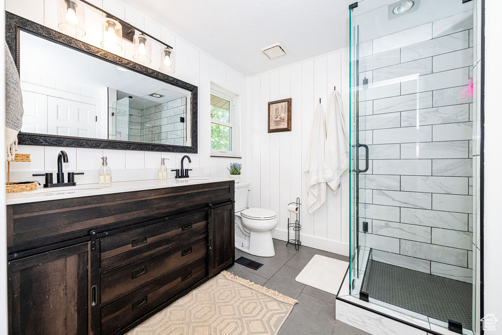 Bathroom with double vanity, a shower stall, and tile patterned floors