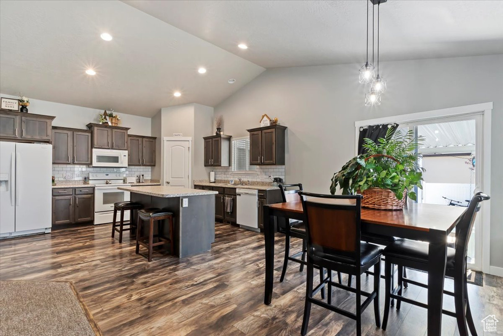 Dining room with dark wood-style flooring, lofted ceiling, and recessed lighting