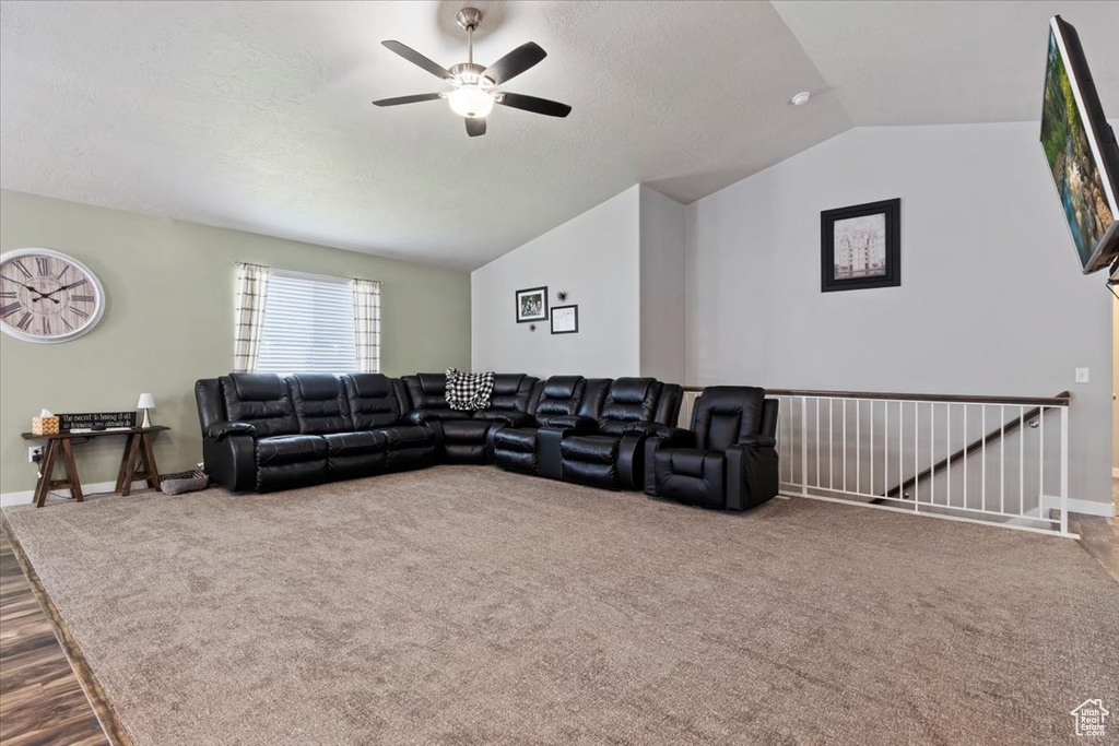 Living area with lofted ceiling, ceiling fan, carpet flooring, wood finished floors, and a textured ceiling