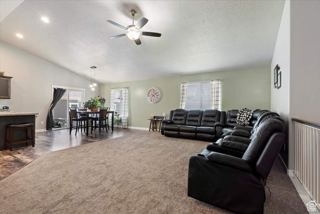 Living area featuring dark carpet, ceiling fan, a textured ceiling, vaulted ceiling, and recessed lighting