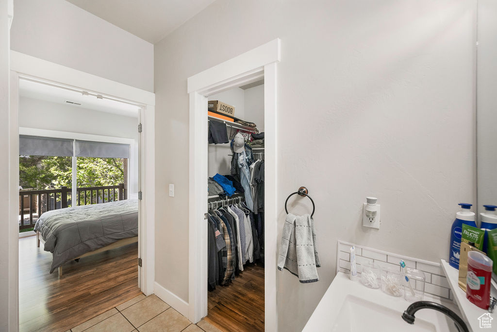 Bathroom with a walk in closet, wood finished floors, and connected bathroom
