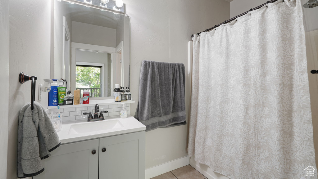 Bathroom with vanity, tile patterned floors, decorative backsplash, and a shower with shower curtain