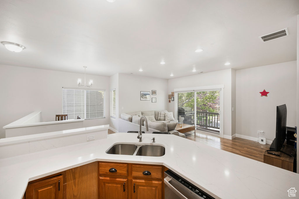 Kitchen featuring open floor plan, a chandelier, wood finished floors, dishwasher, and recessed lighting