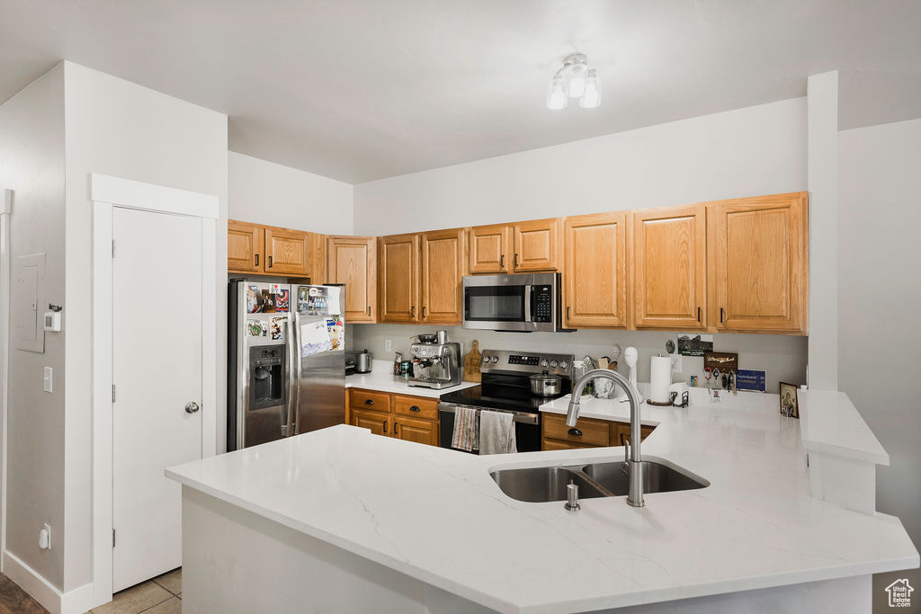 Kitchen featuring appliances with stainless steel finishes, a peninsula, and light stone countertops