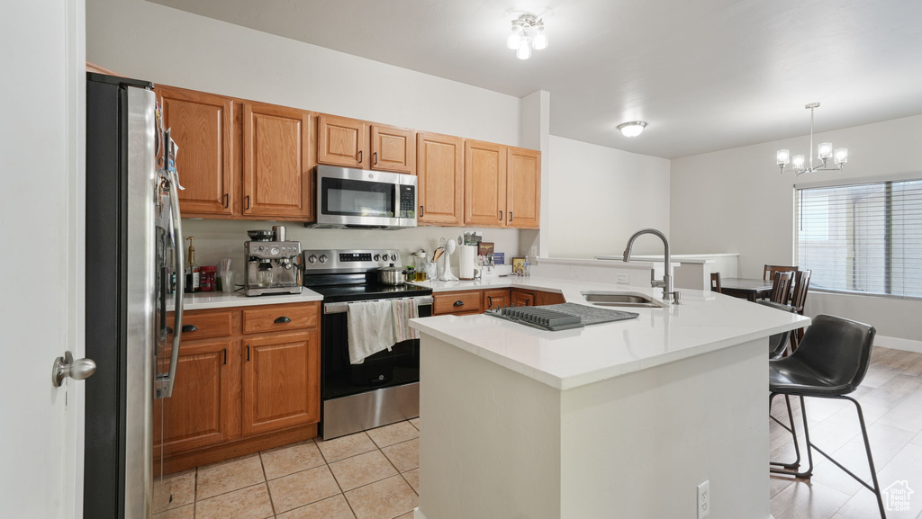 Kitchen featuring appliances with stainless steel finishes, a kitchen breakfast bar, light countertops, and light tile patterned flooring