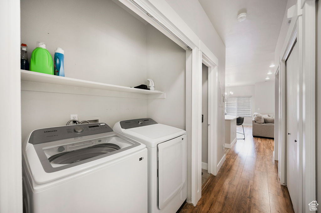 Washroom with washing machine and clothes dryer and wood finished floors