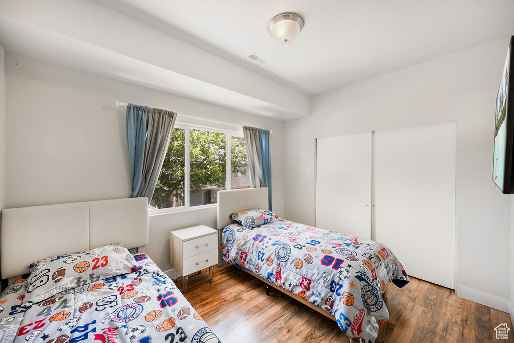 Bedroom with wood finished floors and a closet