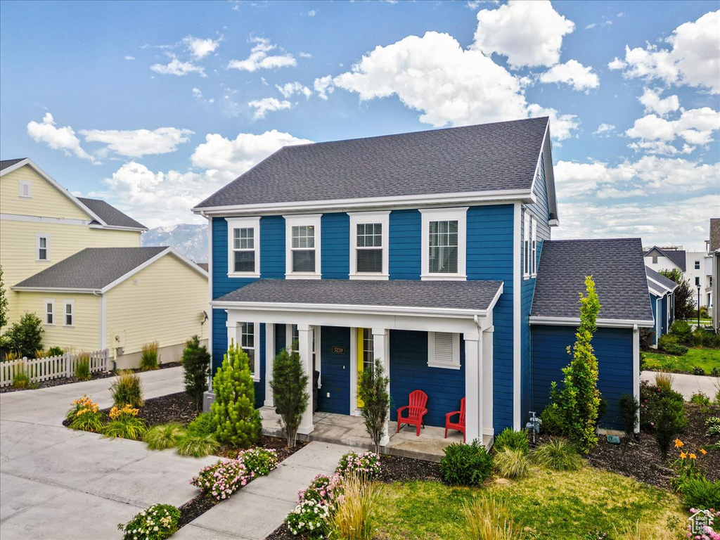Colonial home featuring a porch, roof with shingles, concrete driveway, and a residential view