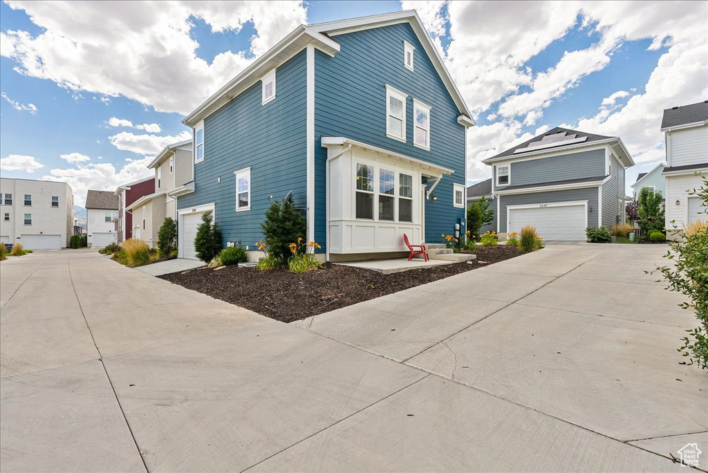 View of front of property featuring driveway, a residential view, and a garage