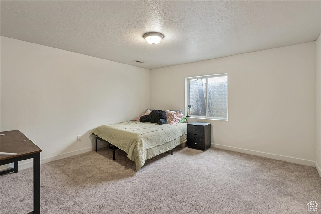 Carpeted bedroom featuring a textured ceiling and baseboards