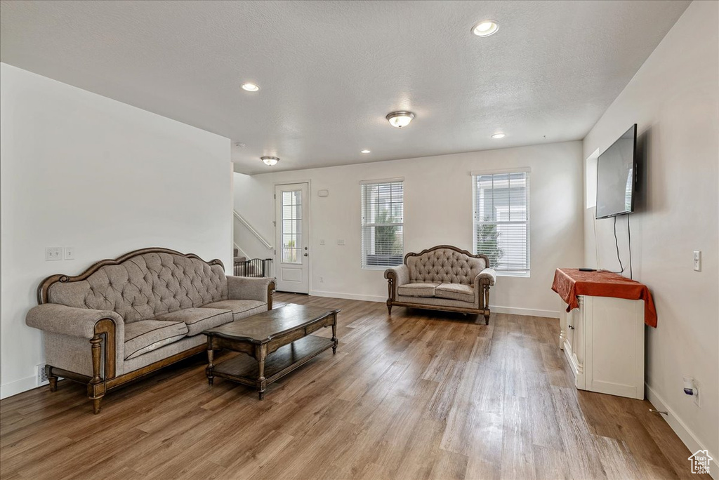Living area with light wood-style flooring, stairway, and recessed lighting