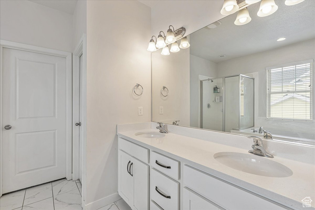 Full bath featuring marble look tiles, a stall shower, double vanity, and a garden tub