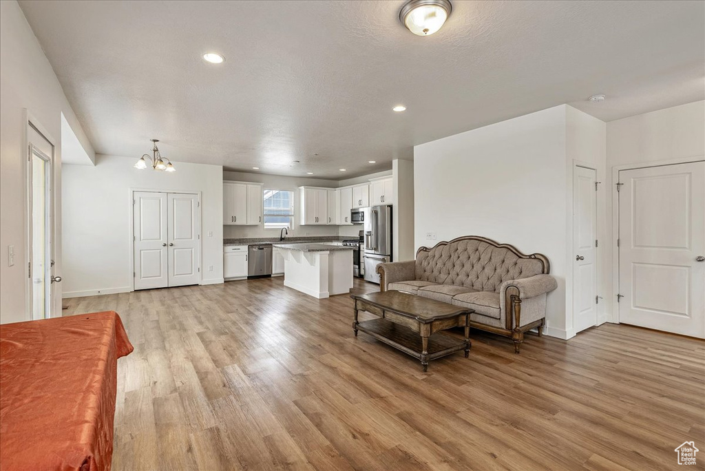Living room with a chandelier, light wood-style flooring, and recessed lighting
