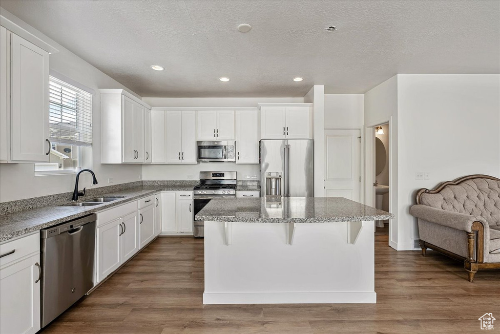 Kitchen with appliances with stainless steel finishes, a center island, white cabinetry, recessed lighting, and a textured ceiling