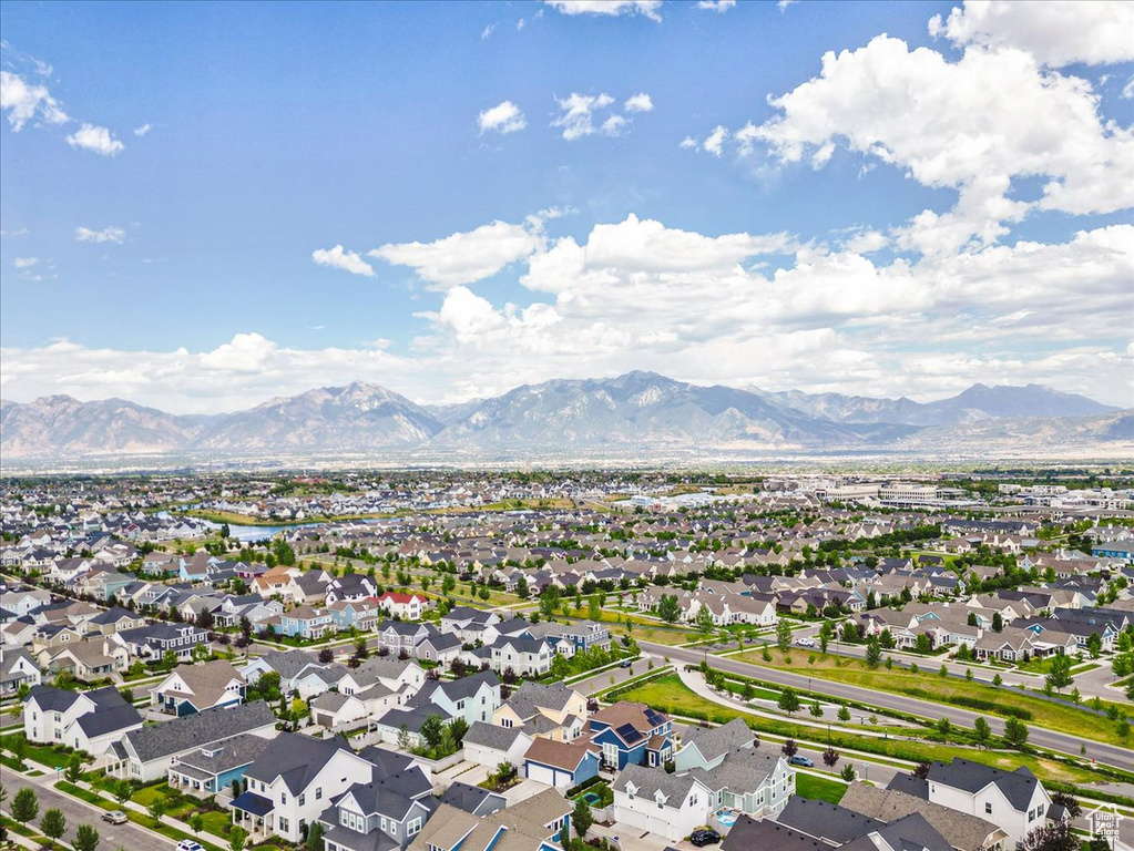 Aerial view of property and surrounding area featuring mountains and nearby suburban area