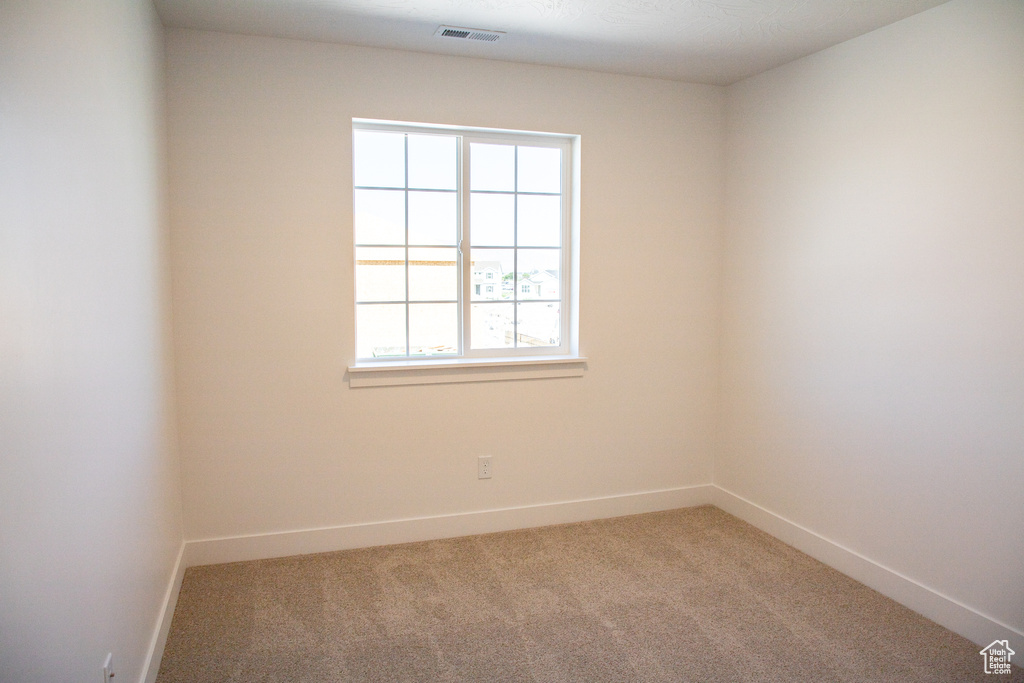 Carpeted spare room featuring baseboards