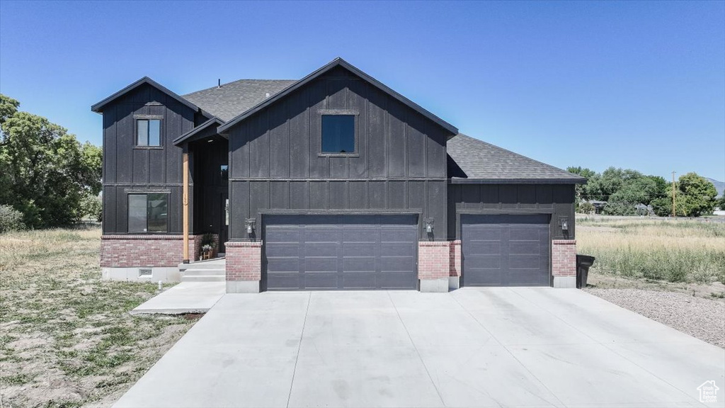 Modern farmhouse style home with brick siding, board and batten siding, and roof with shingles