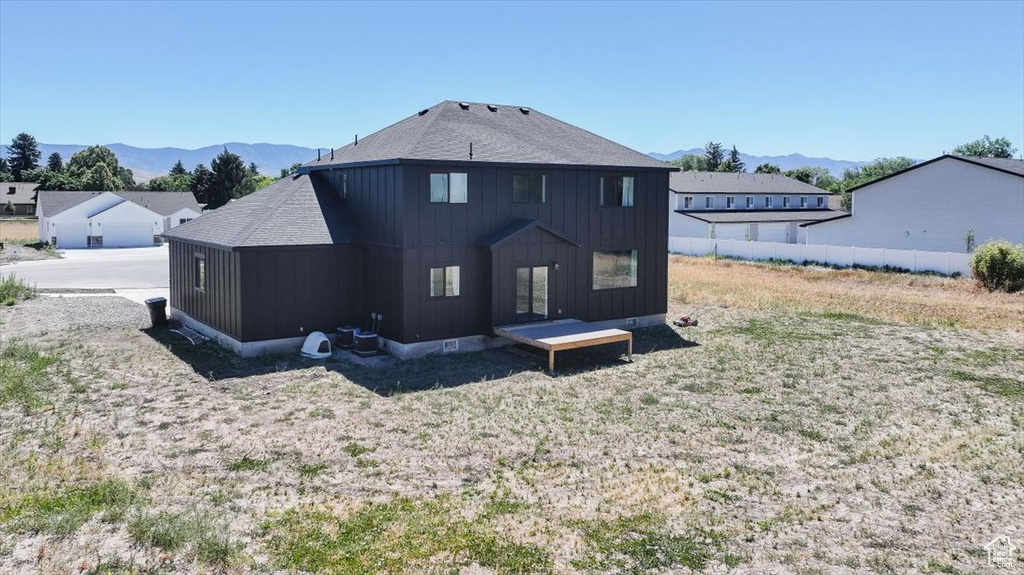 Back of property with a mountain view, board and batten siding, and roof with shingles