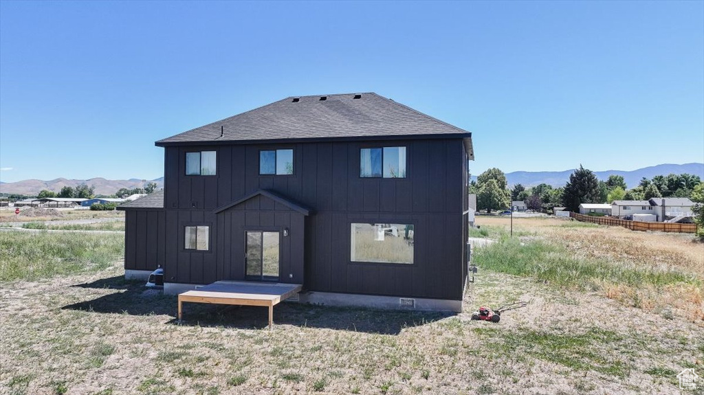 Back of property featuring a mountain view, board and batten siding, and roof with shingles