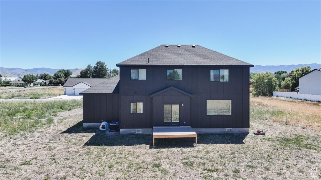 Back of property with a mountain view, board and batten siding, and a shingled roof