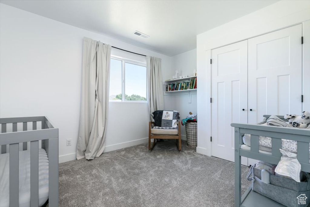 Bedroom with carpet, a crib, and a closet